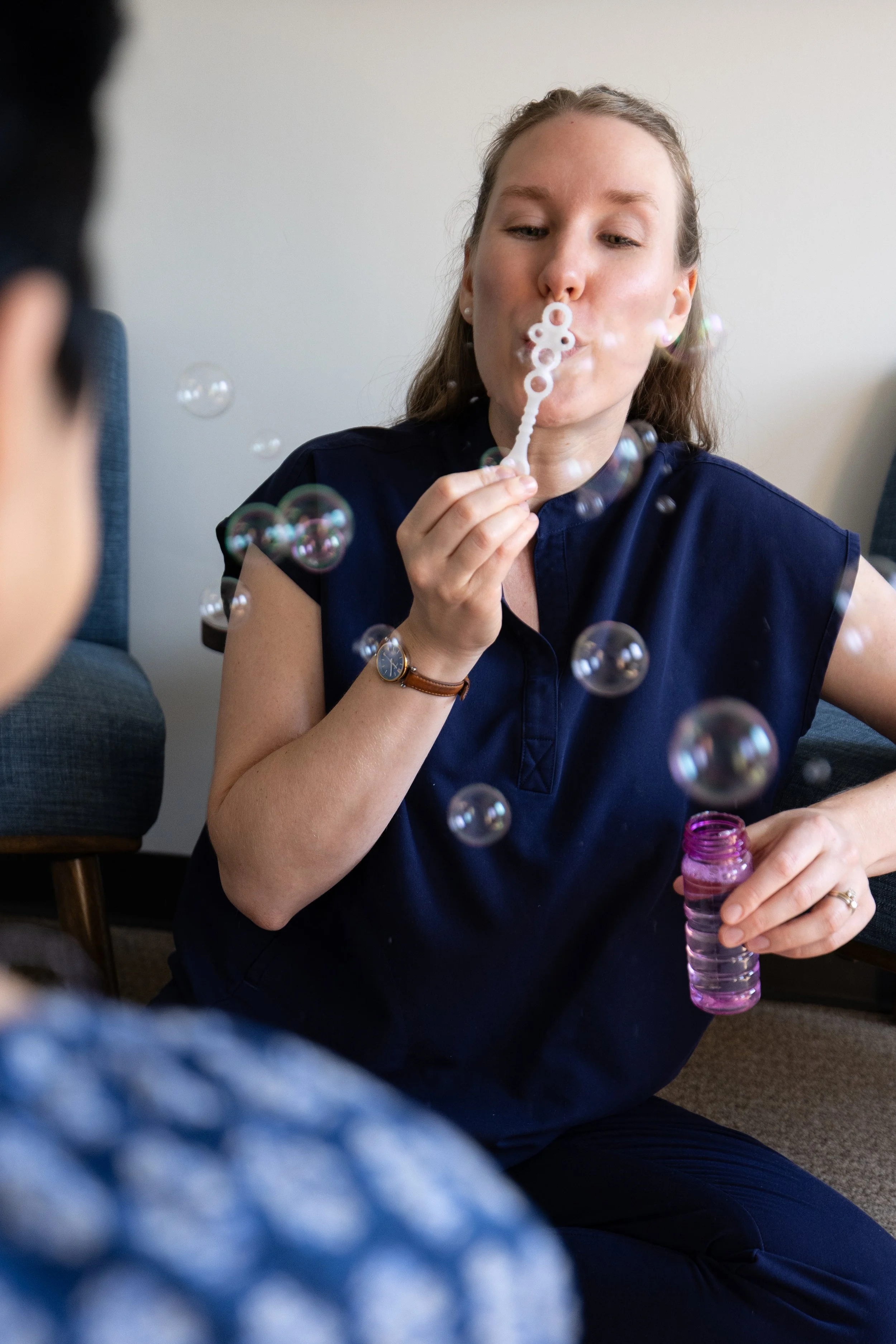 pelvic floor physical therapist blows bubbles in a pediatric session to help patient with breathing