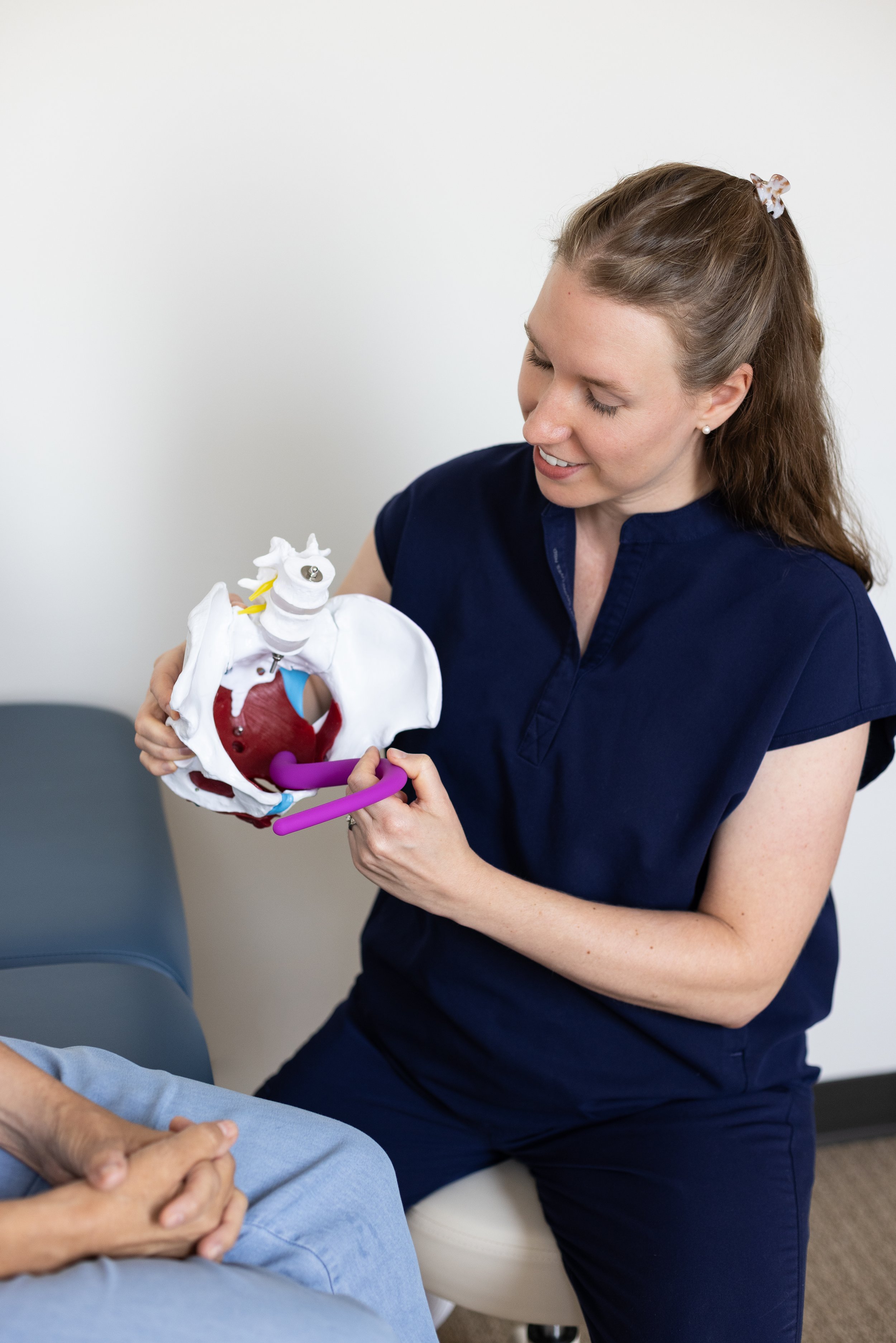 pelvic floor physical therapist shows patient how to use a pelvic wand on a pelvic model