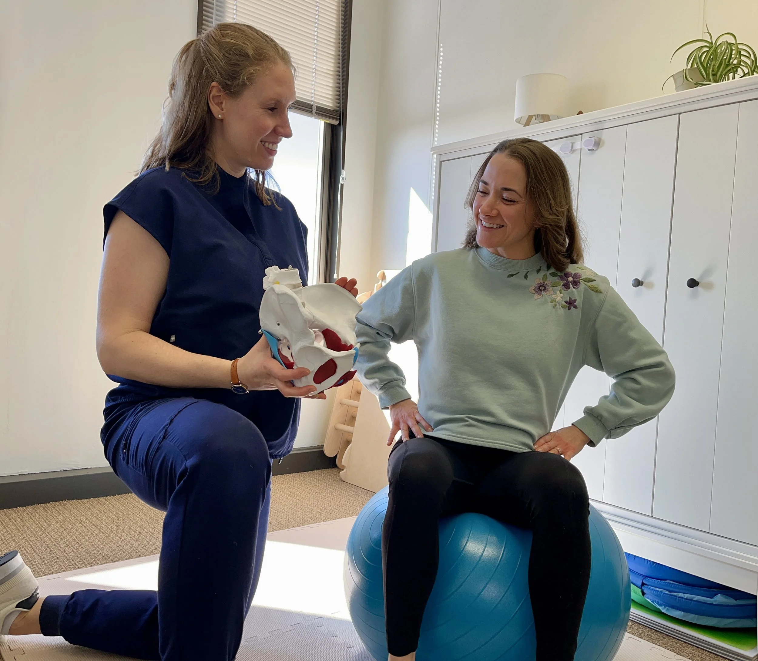 pelvic floor physical therapist teaches patient about pelvic mobility while patient sits on birth ball