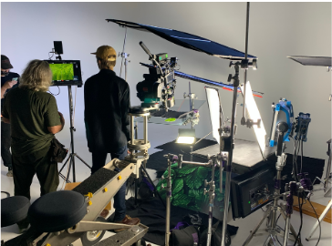Film production crew setting up a green screen studio with various lighting and camera equipment.