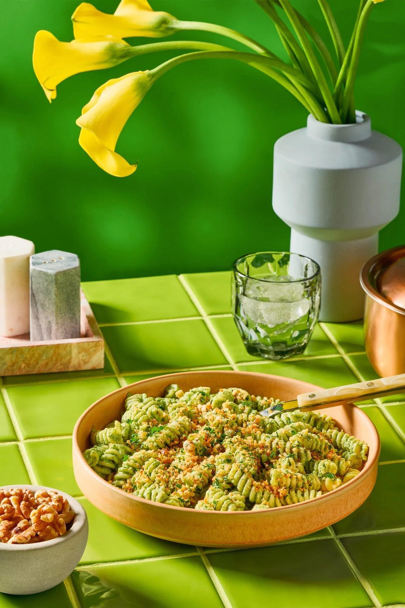 Walnut pesto pasta on a bright green background.