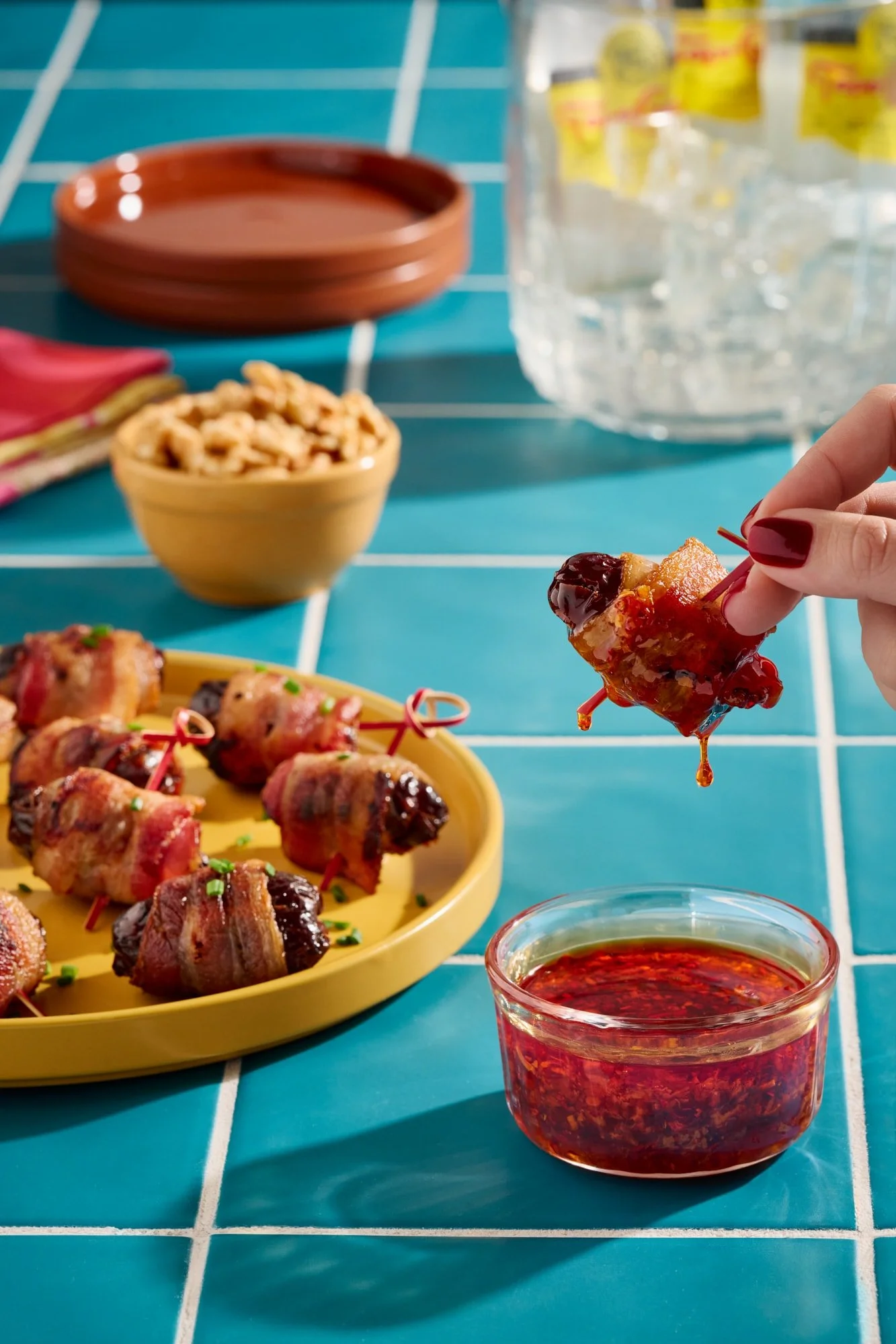 Walnut-stuffed bacon-wrapped dates on colorful blue tile.