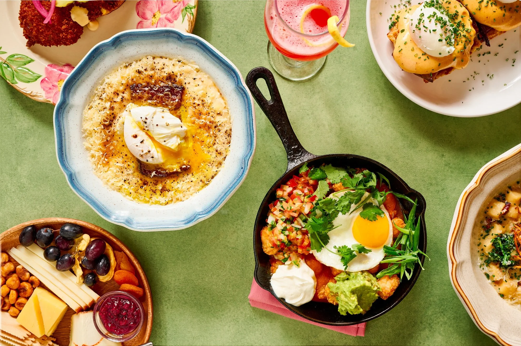 Assorted Mediterranean dishes in colorful bowls on a  green pastel surface.