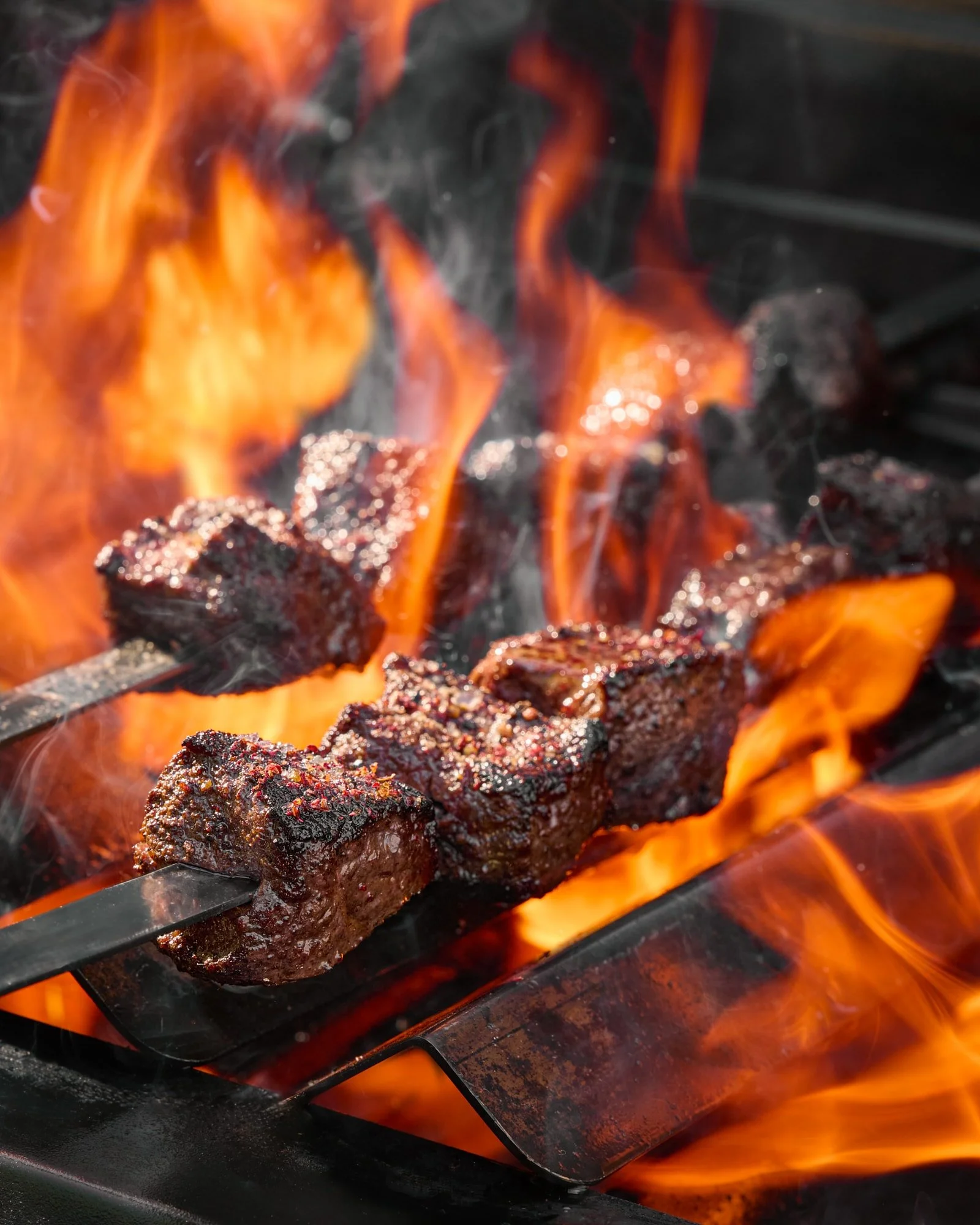 Seasoned steaks grilling over open flames on a barbecue grill