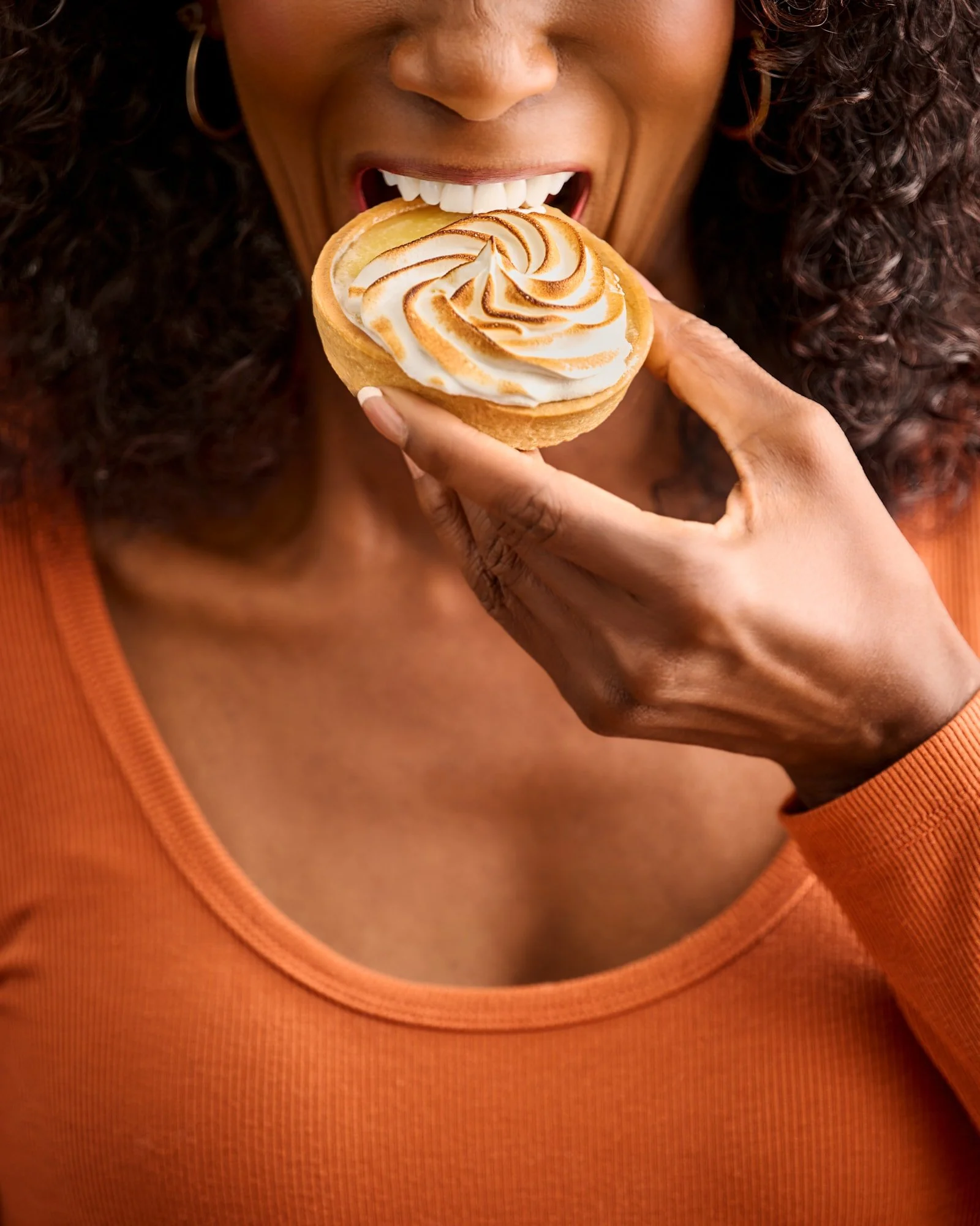 Close-up of a woman holding a toasted meringue tart near her mouth