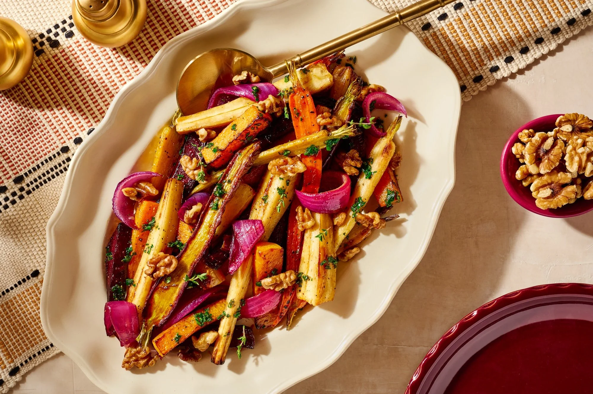 A platter of roasted fall veggies topped with walnuts.