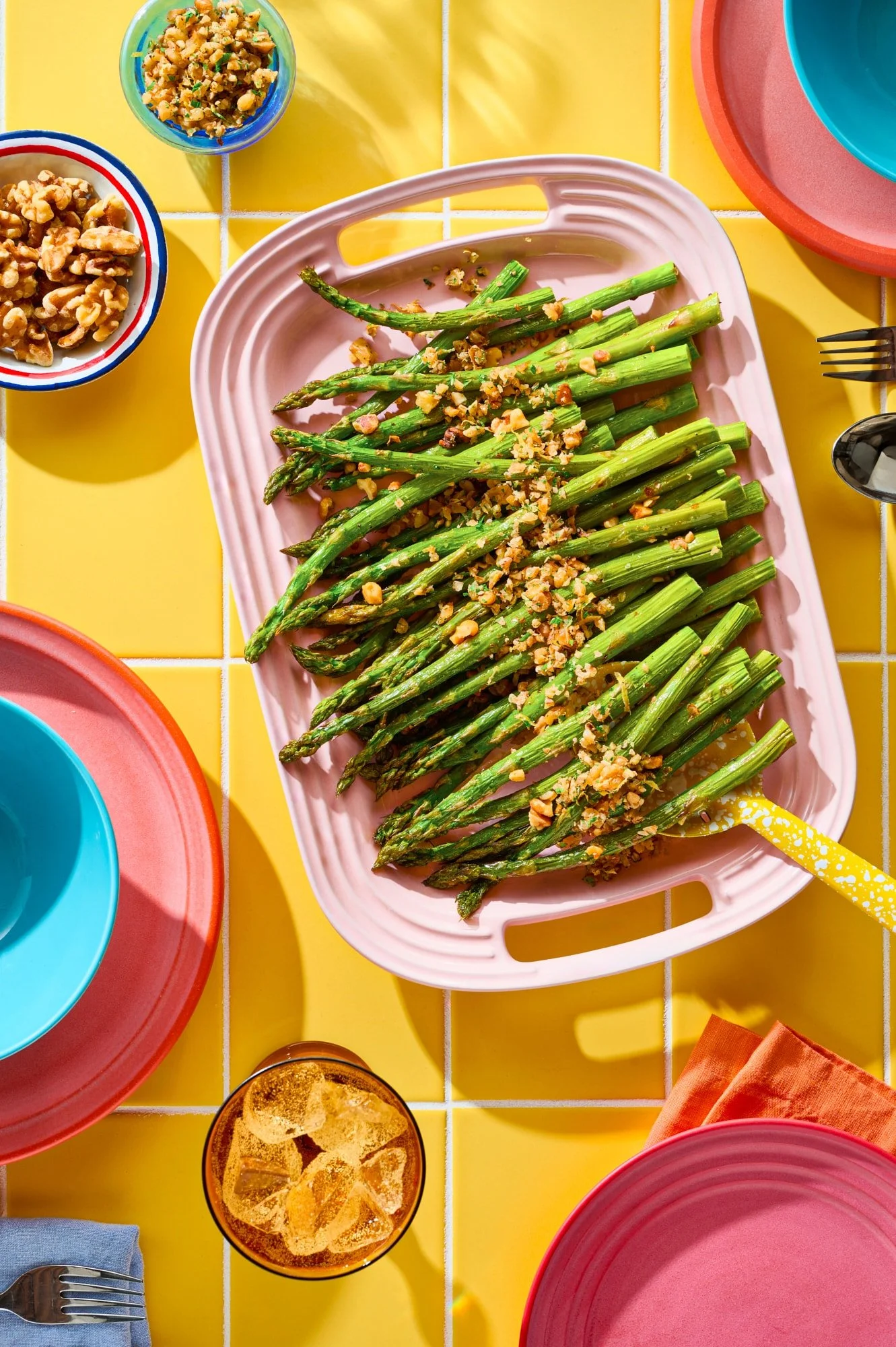 Asparagus topped with walnuts on a springy yellow background.