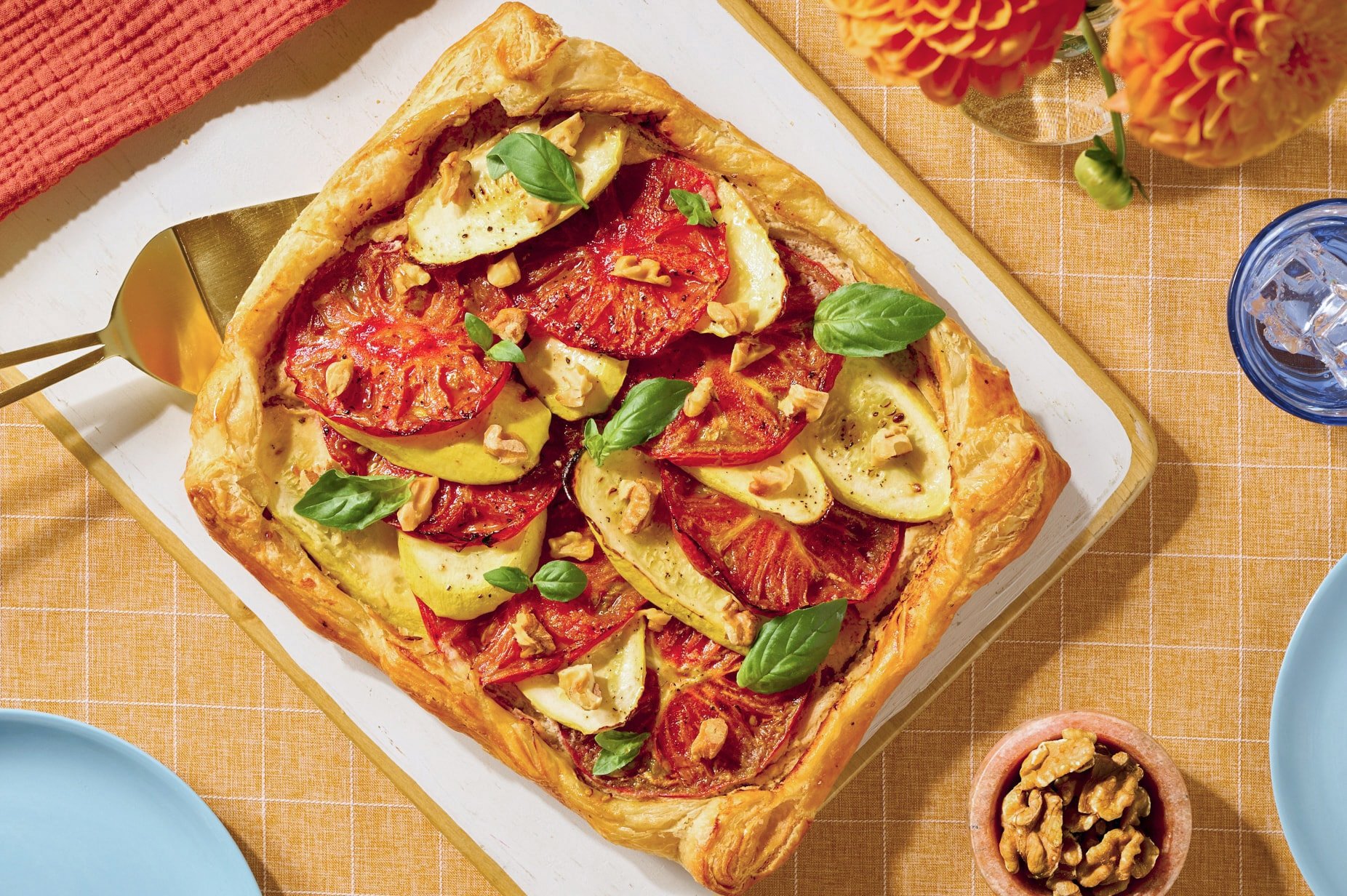 Savory tomato and zucchini puff pastry tart topped with basil and walnuts