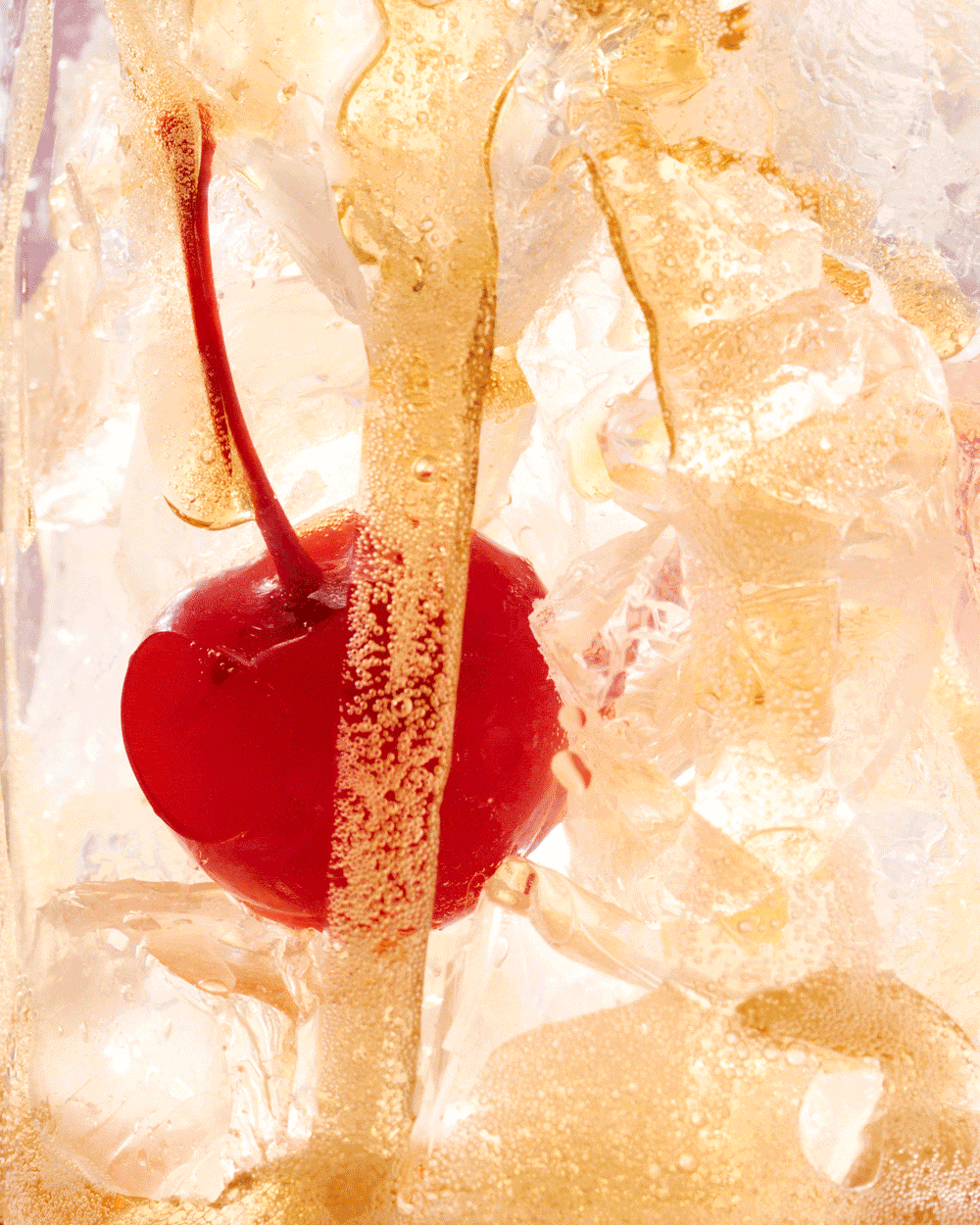 Close-up of cherry coke being poured over ice and a cherry on a textured, translucent surface