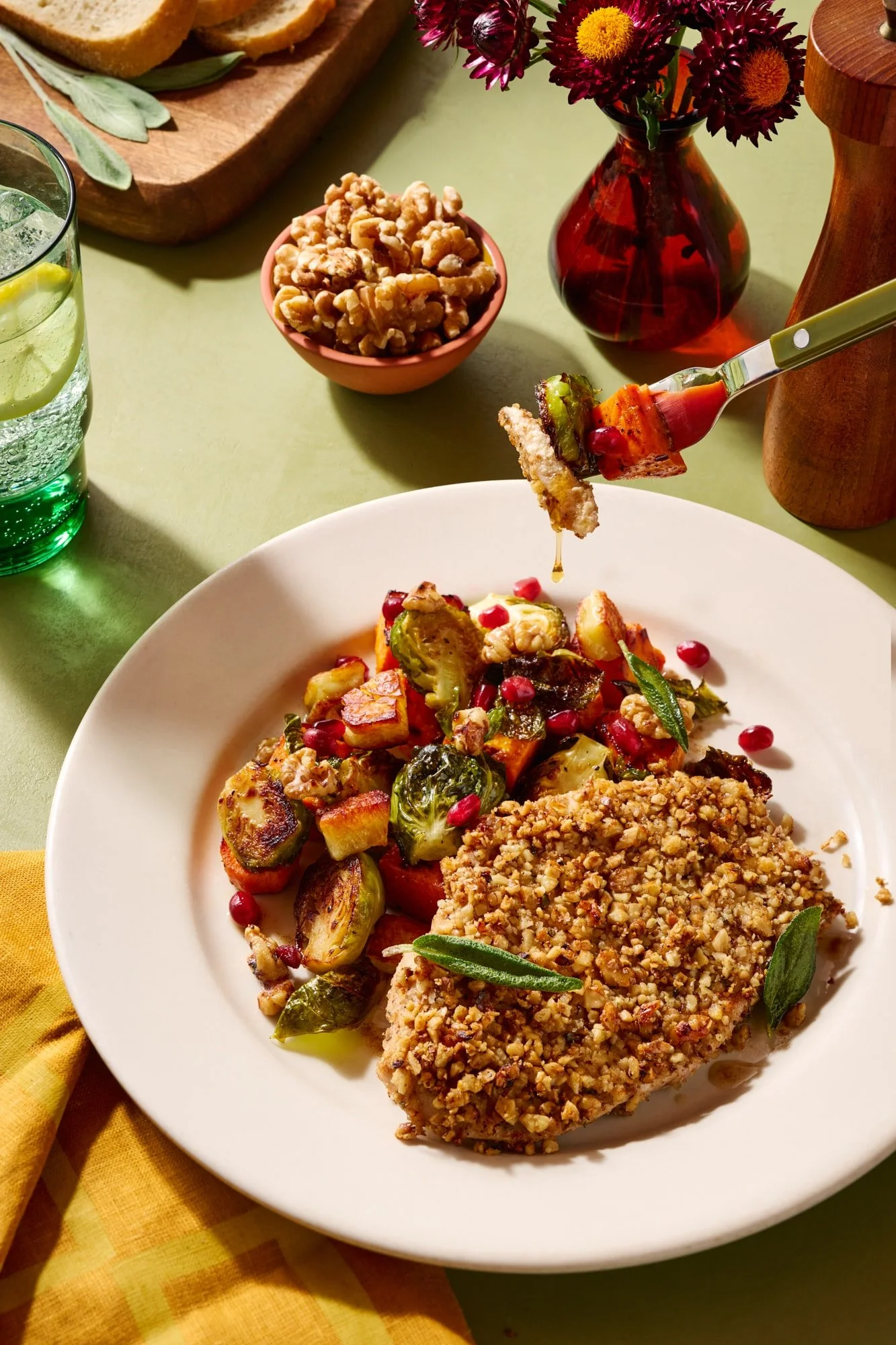 A walnut christed chicken breast with a side of mixed roasted vegetables in a colorful setting.
