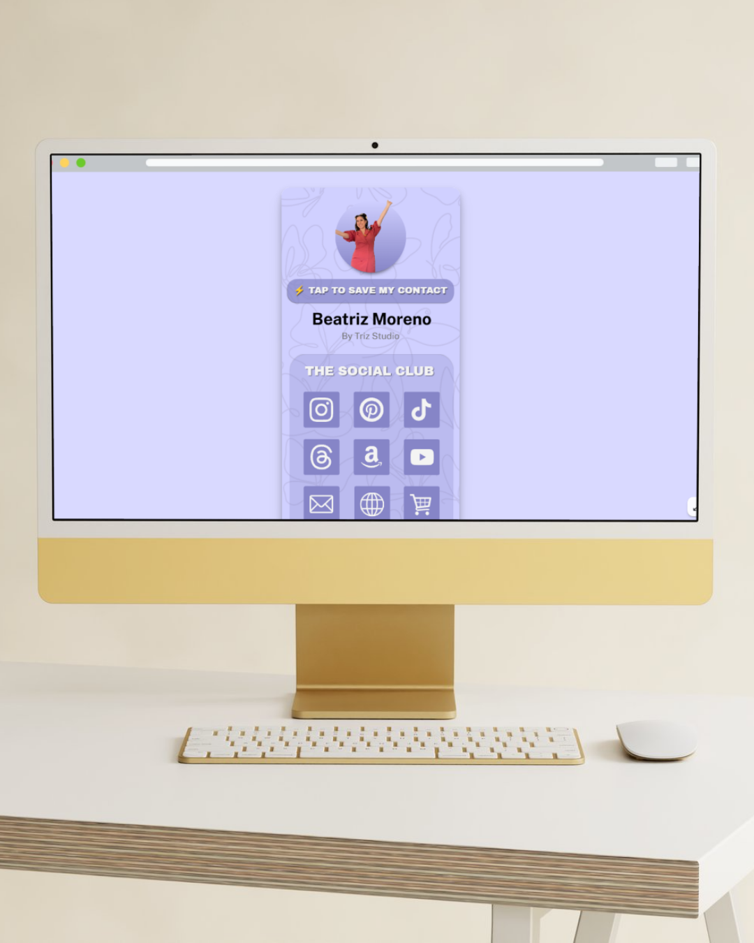 Computer monitor displaying a social media contact card for Beatriz Moreno with icons for various social platforms, set on a minimalist white desk with a wireless keyboard and mouse.