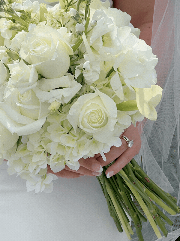 Bridal white flowers and roses bouquet with large engagement ring.