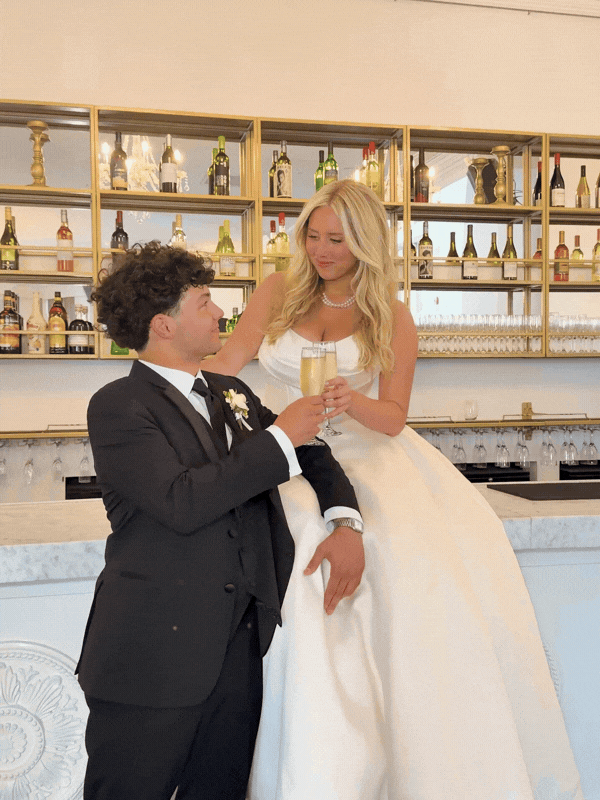 Bride and groom sitting on a marble bar in Omaha Empire Room with champagne.