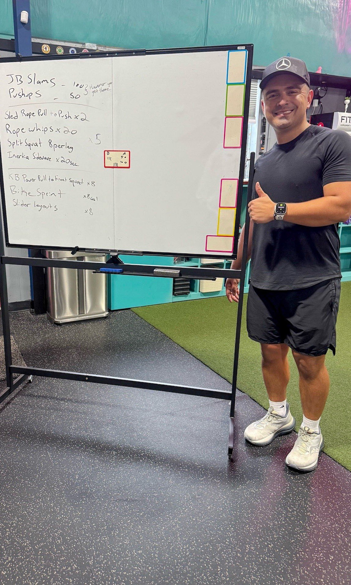 Pink Llama Fitness coach beside a whiteboard outlining the workout plan