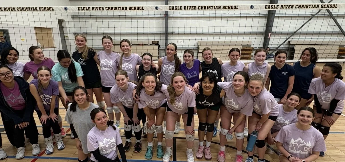 Group of young female volleyball players in gymnasium posing after a match at Eagle River Christian School.