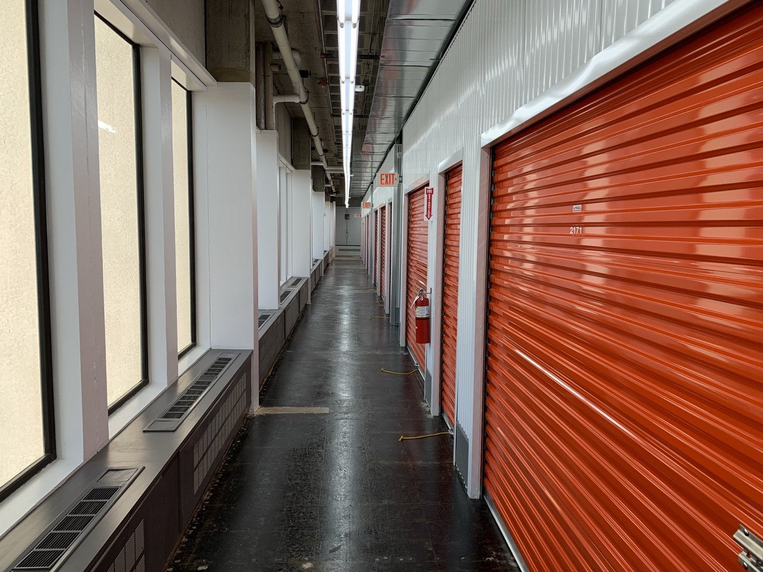 Completed climate-controlled self-storage corridor with orange roll-up doors inside the Framingham U-Haul facility.