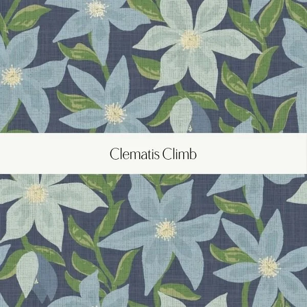 A fabric pattern featuring light blue clematis flowers with white centers and green leaves on a dark background, labeled 'Clematis Climb'.
