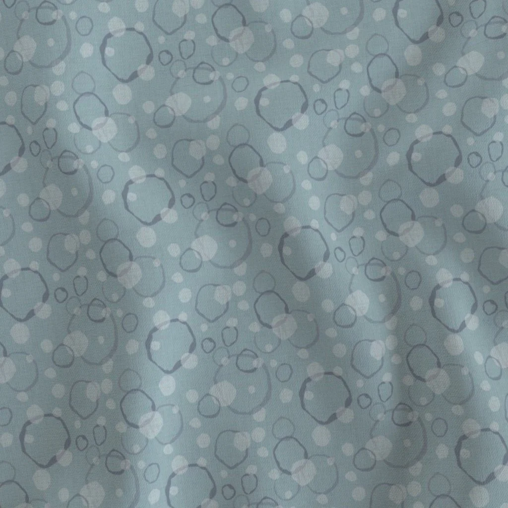 Light blue fabric patterned with overlapping circles and dots in varying shades of grey and white.