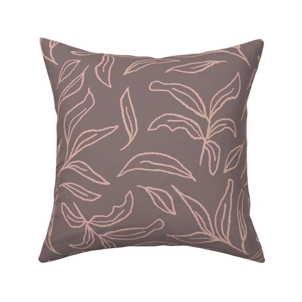 Dusty mauve-brown throw pillow featuring abstract, painterly line drawings of leafy botanical branches in soft blush pink.