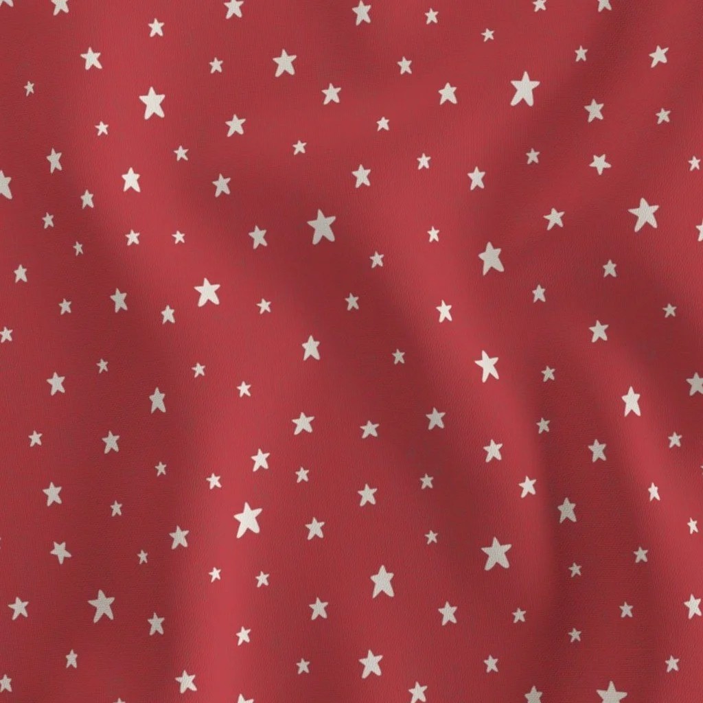 Deep poppy red woven fabric scattered with hand drawn small, cream-colored five-pointed stars of varying sizes.