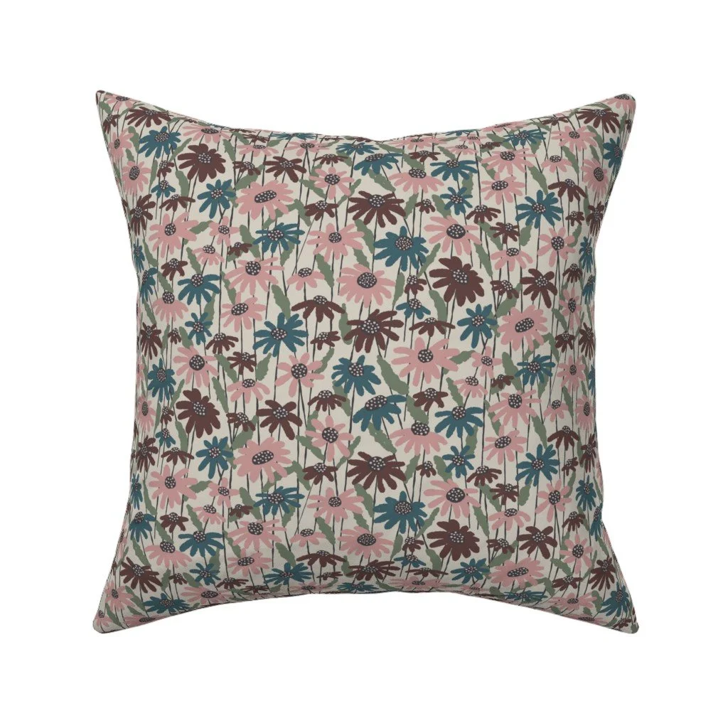 A decorative square pillow with a floral pattern featuring pink, blue, and brown flowers with green leaves on a light background.