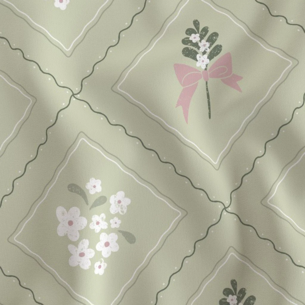 Sage green fabric with a repeating quilted pattern of squares outlined in wavy lines, containing illustrations of small white flower bouquets and pink ribbons by Una Somerville.