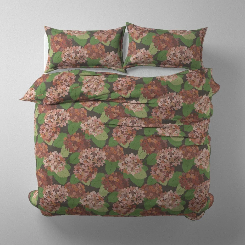 Overhead mockup of a double bed featuring a dark charcoal duvet cover and pillows printed with lush autumn hydrangea blooms in terracotta, blush, and coral tones.