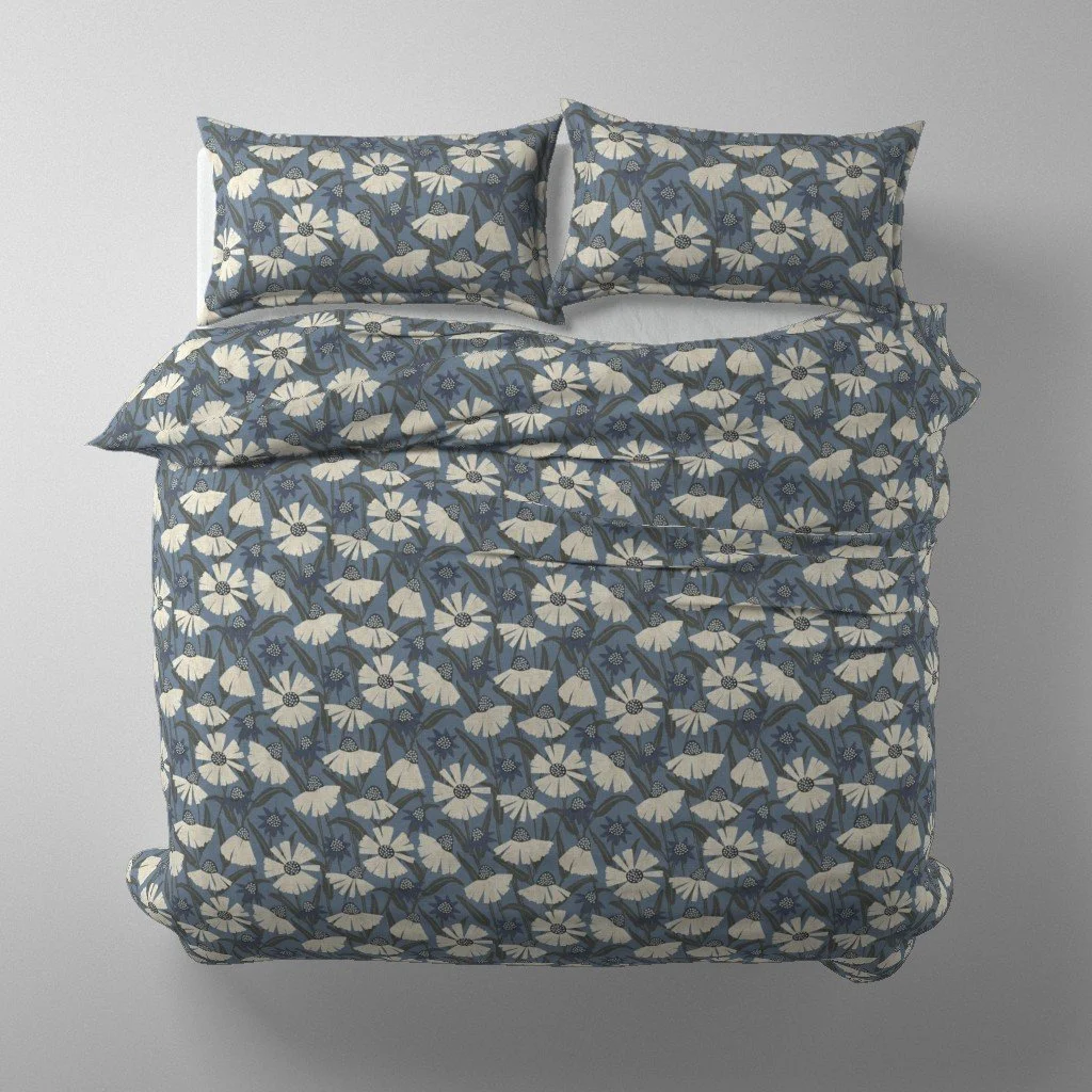 A bed with a floral print bedding set in shades of blue and white, including two pillows and a comforter.