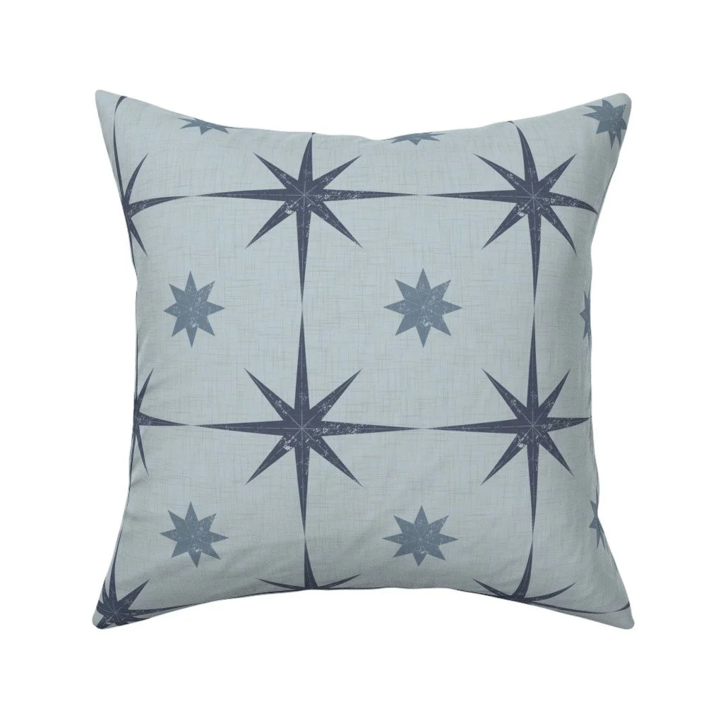 Pale powder-blue textured throw pillow featuring distressed dark navy compass stars and starbursts.