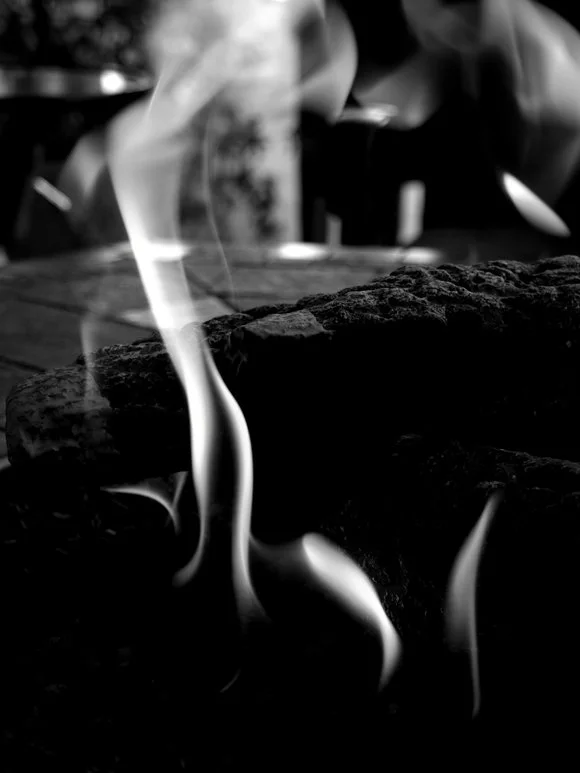 Close-up of fire with visible flames and smoke, black and white photograph.