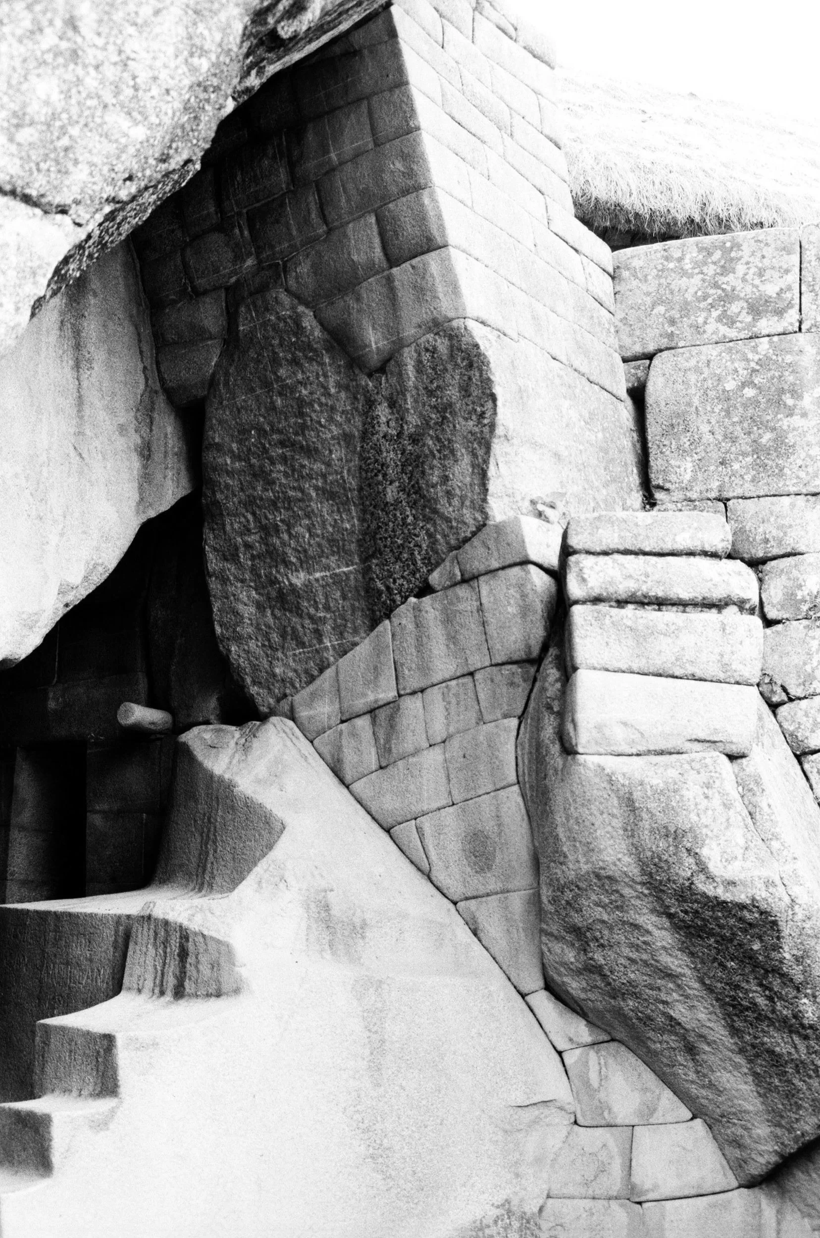 Close-up of large stone blocks and irregular rocks forming part of an ancient stone wall or monument, with some stones carved or shaped.