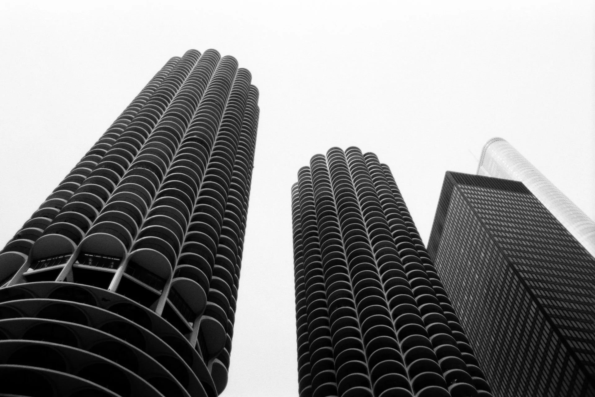 Black and white photo of three tall skyscrapers viewed from below, with a cloudy sky in the background.