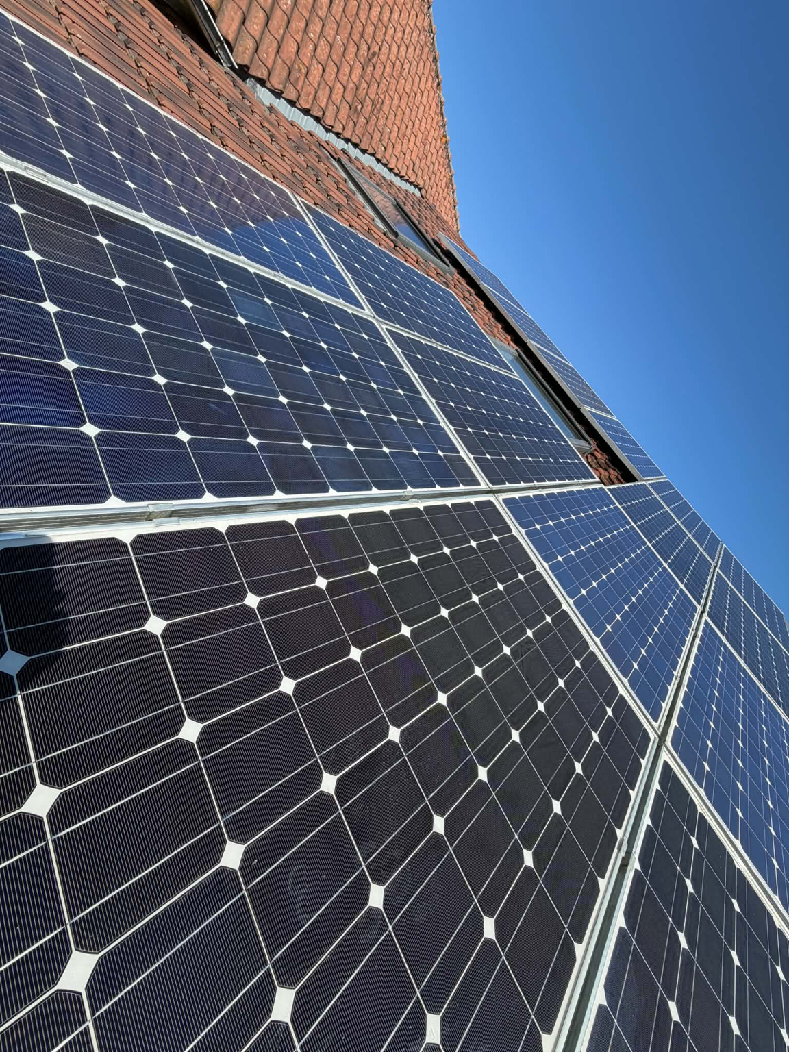 Panneaux solaires installés sur un toit en pente en construction ou rénovation, avec un ciel bleu clair.