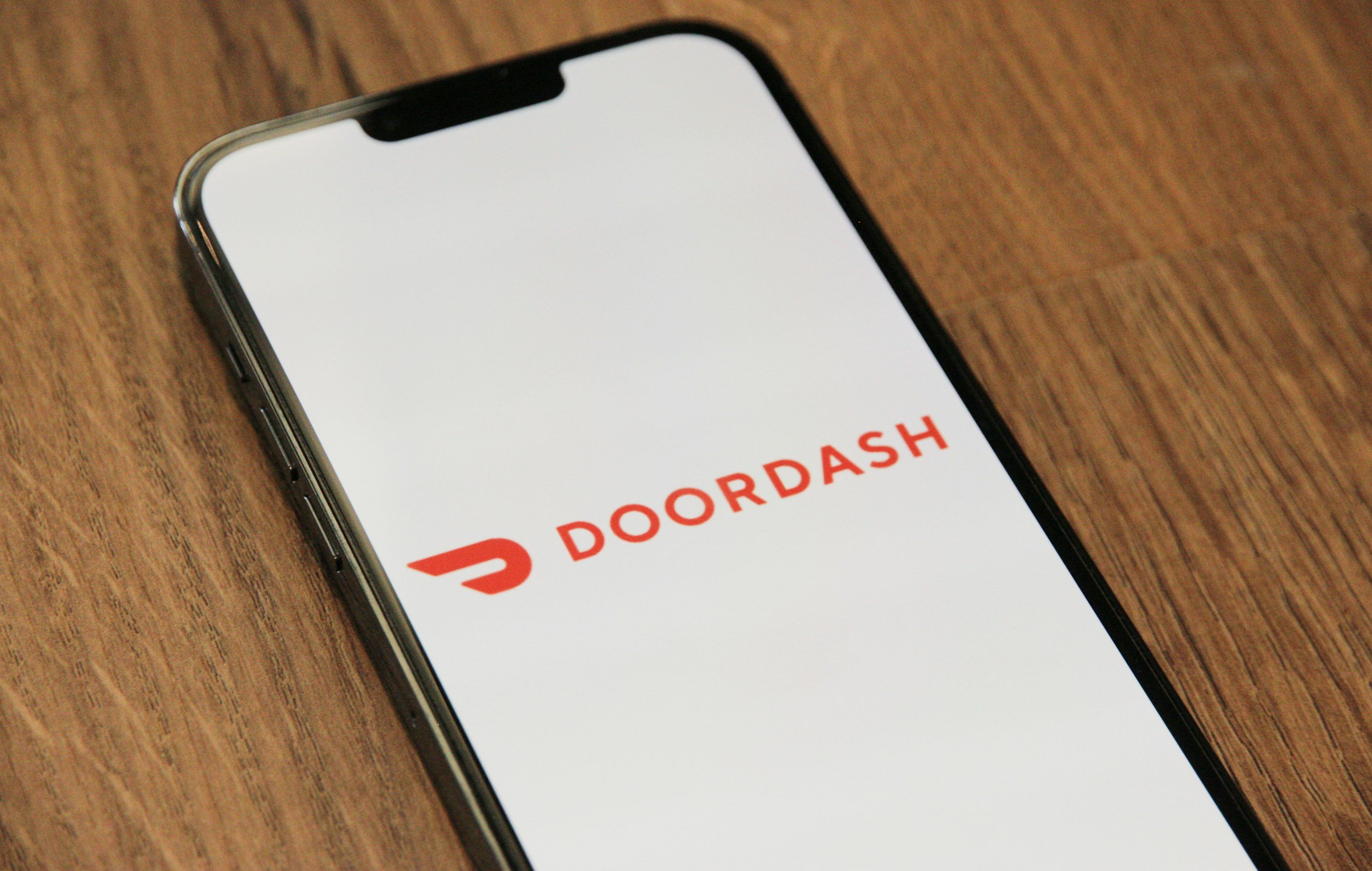 An iPhone with the DoorDash app open on the screen, placed on a wooden surface.