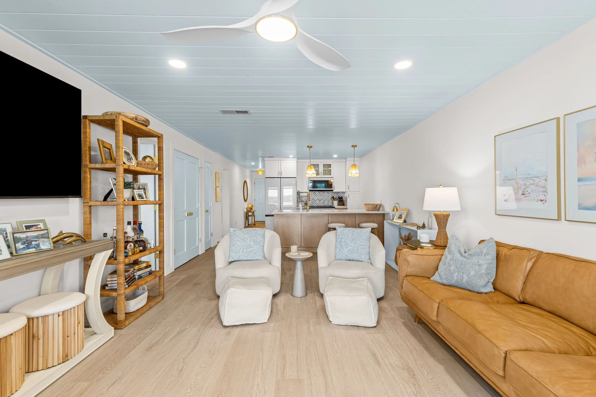 Renovated open living space with light wood floors, comfortable seating, and adjoining kitchen.