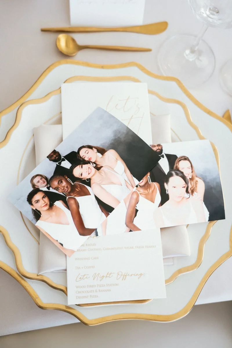 Elegant table setting with gold utensils, a gold-rimmed white plate, photographs of a diverse group of people in formal attire, and a menu card for a wedding or special event.