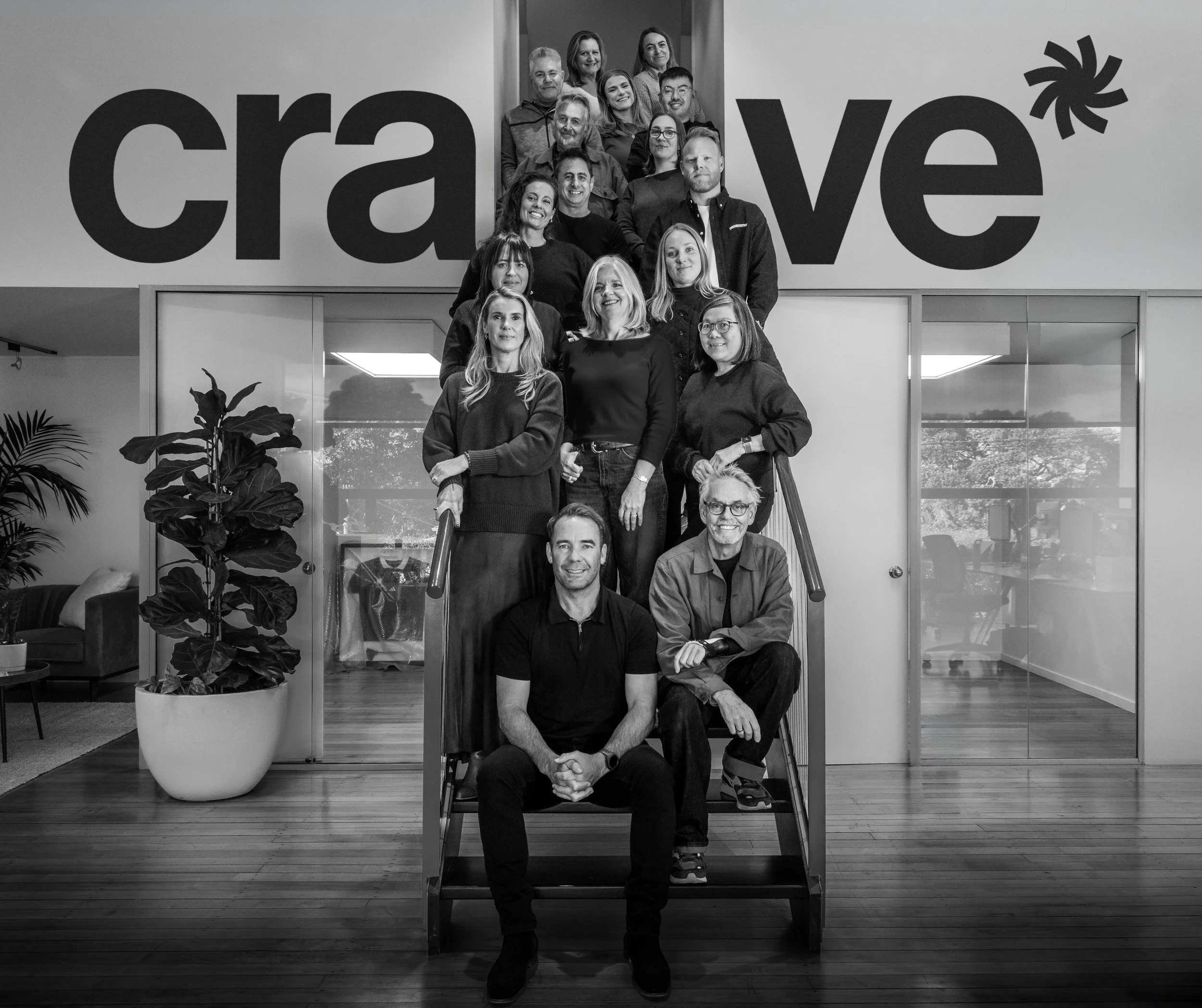 Crave Group team photo on office staircase, wordmark backdrop.