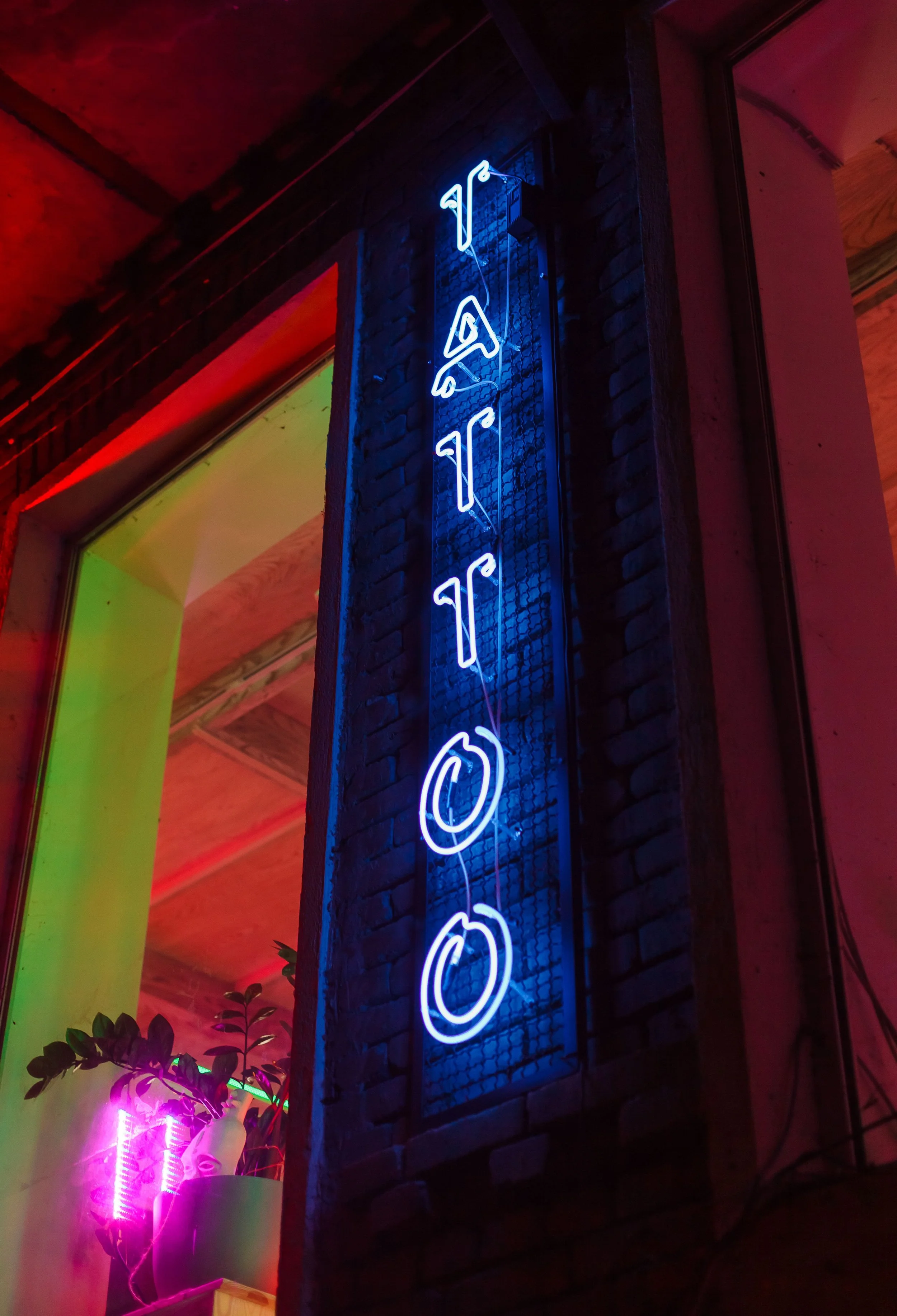Neon Tattoo sign on brick at night