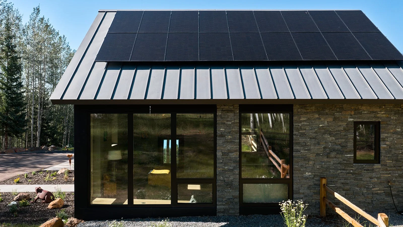 Rooftop solar panels and triple pane European windows with stone exterior detail on a high-performance home in the Gunnison Valley