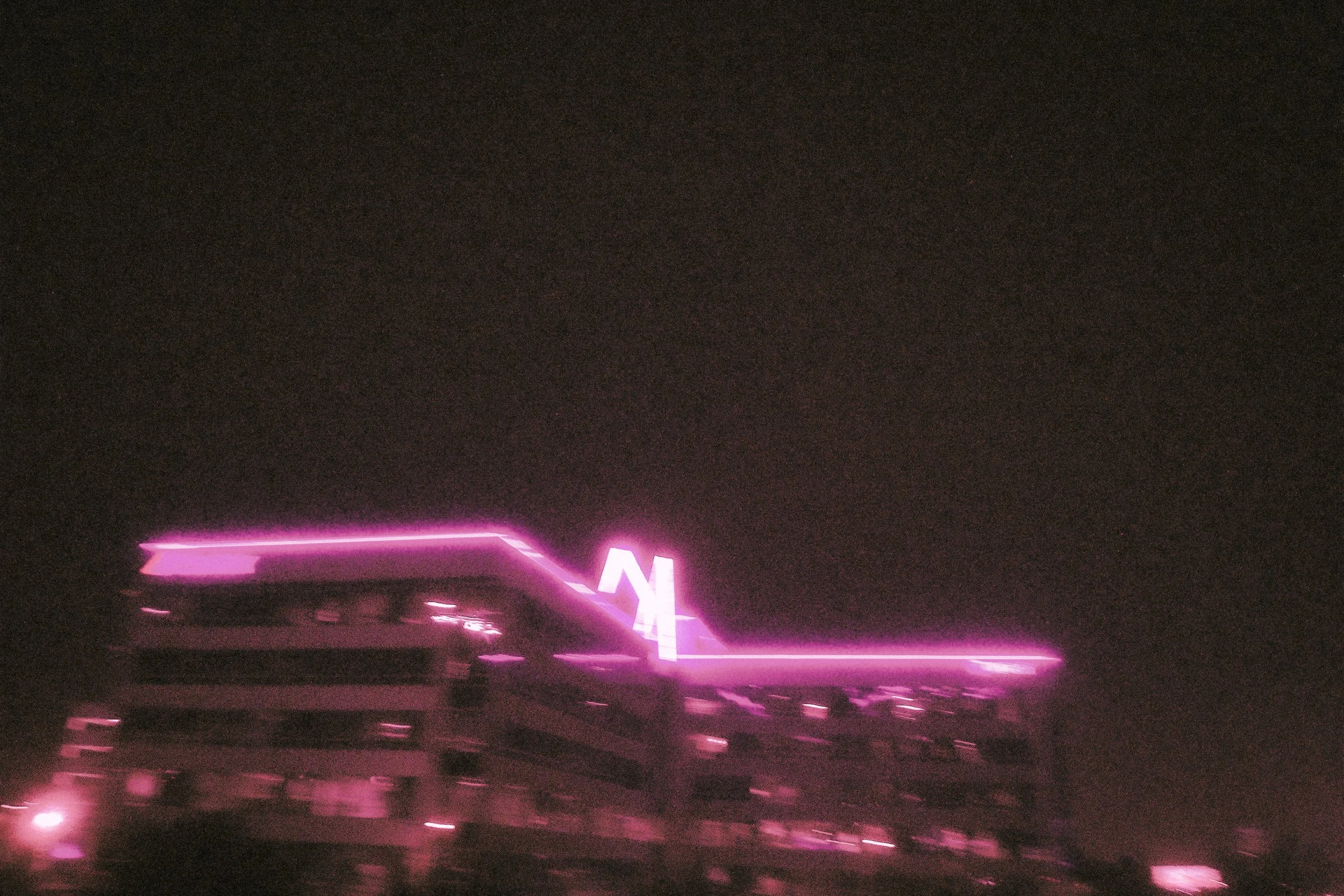 Blurry pink neon building lights against a dark night sky