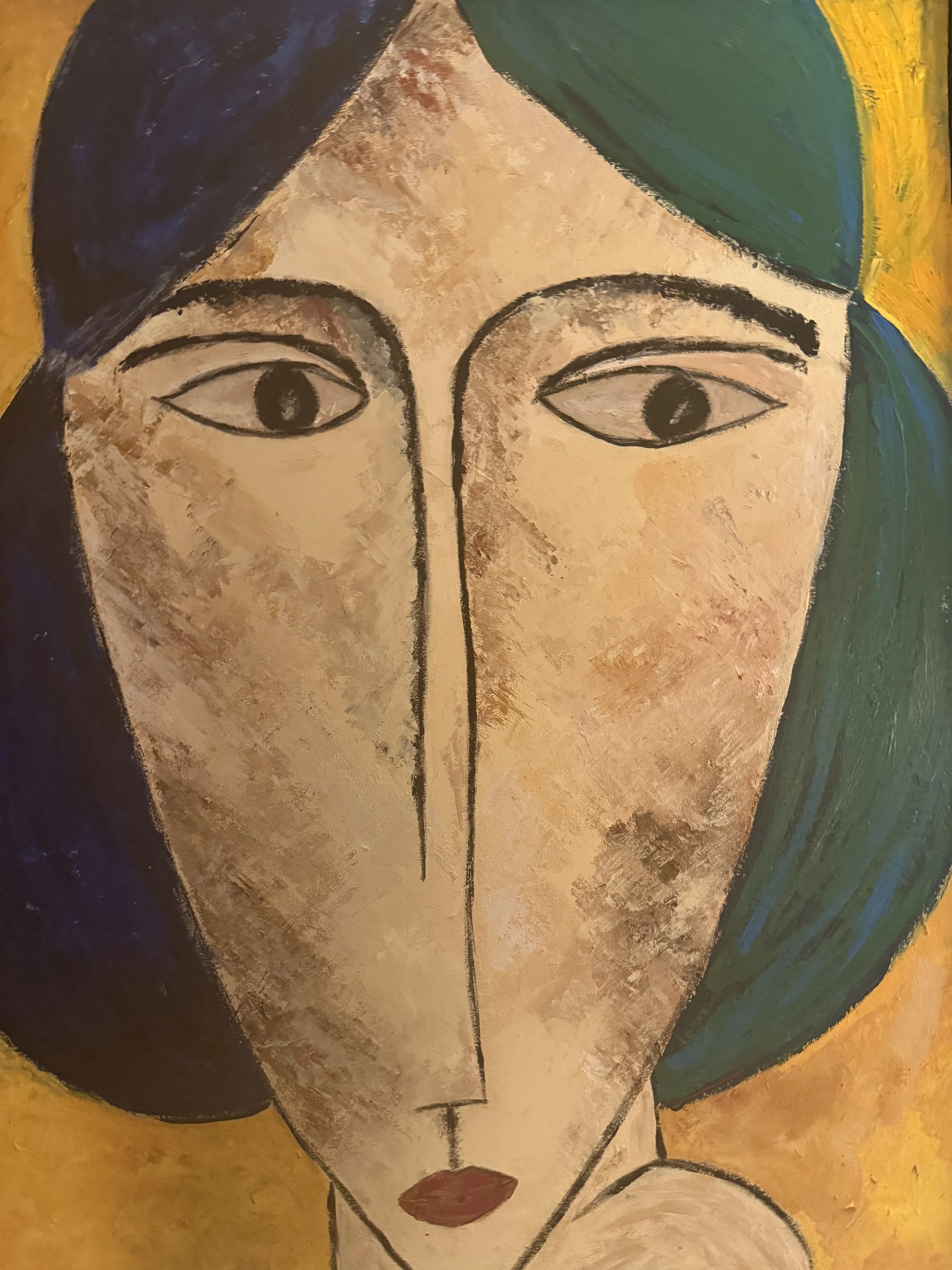Close-up of an abstract painting of a woman's face with closed eyes, dark hair, with colorful background in shades of yellow, green, and dark blue.