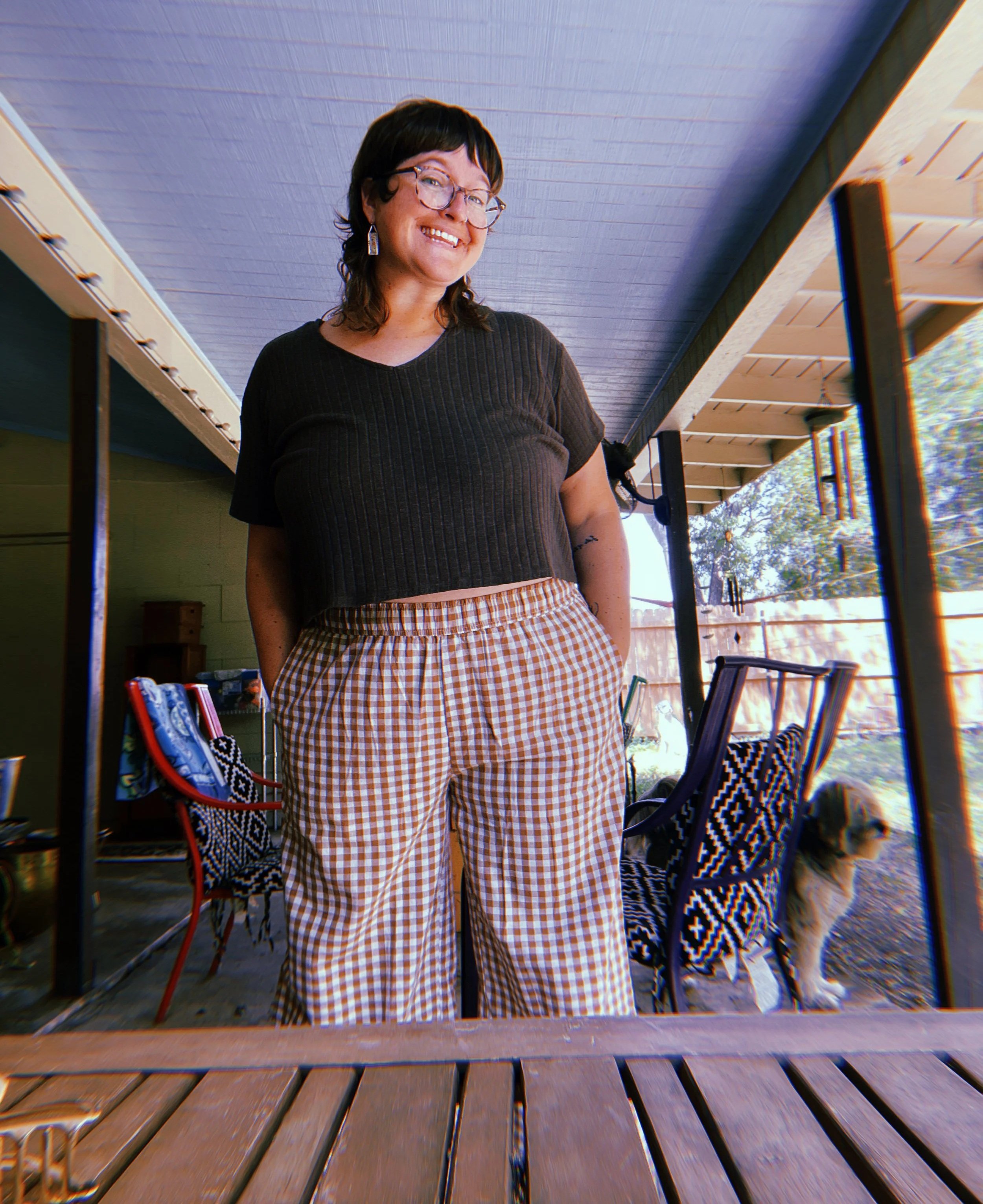 A woman with glasses and dark hair smiling in a backyard patio area.