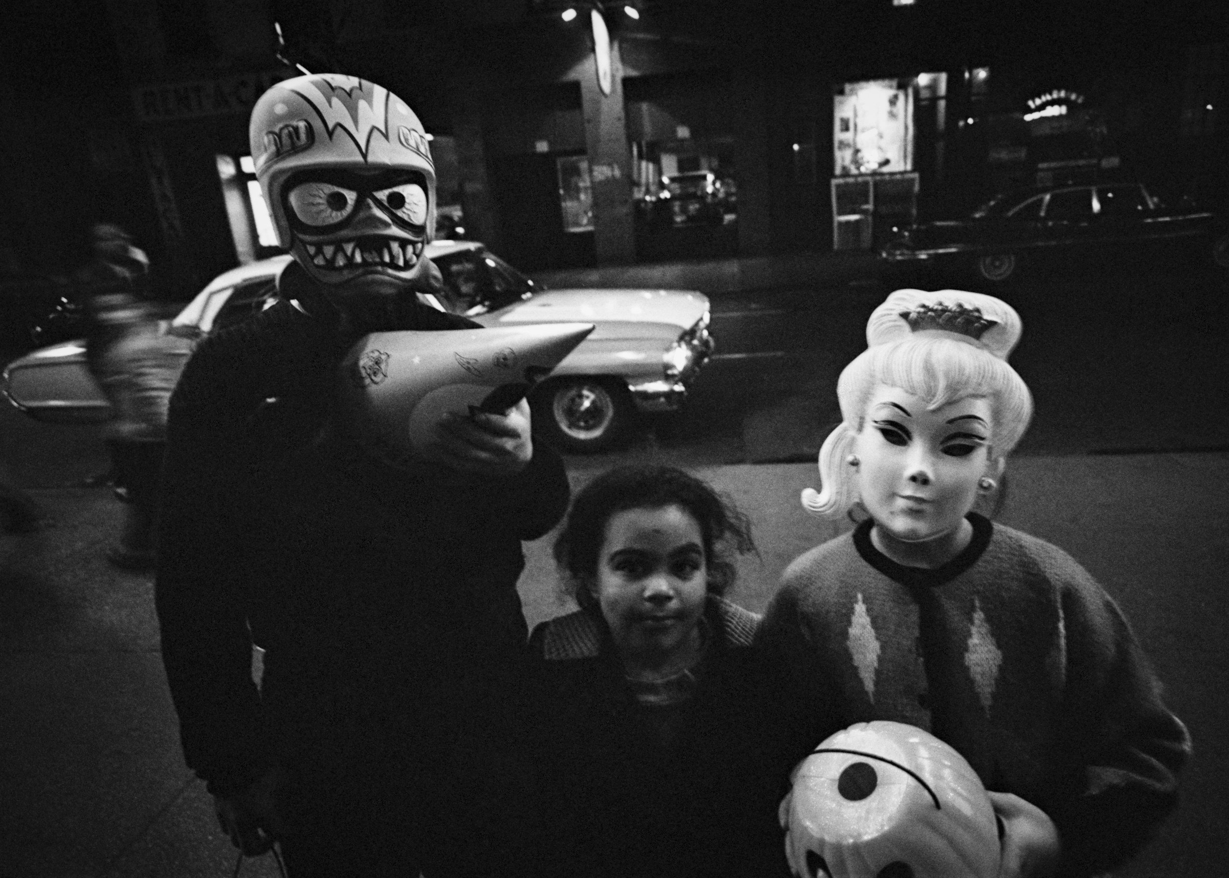 Three children wearing homemade Halloween costumes with masks and capes.
