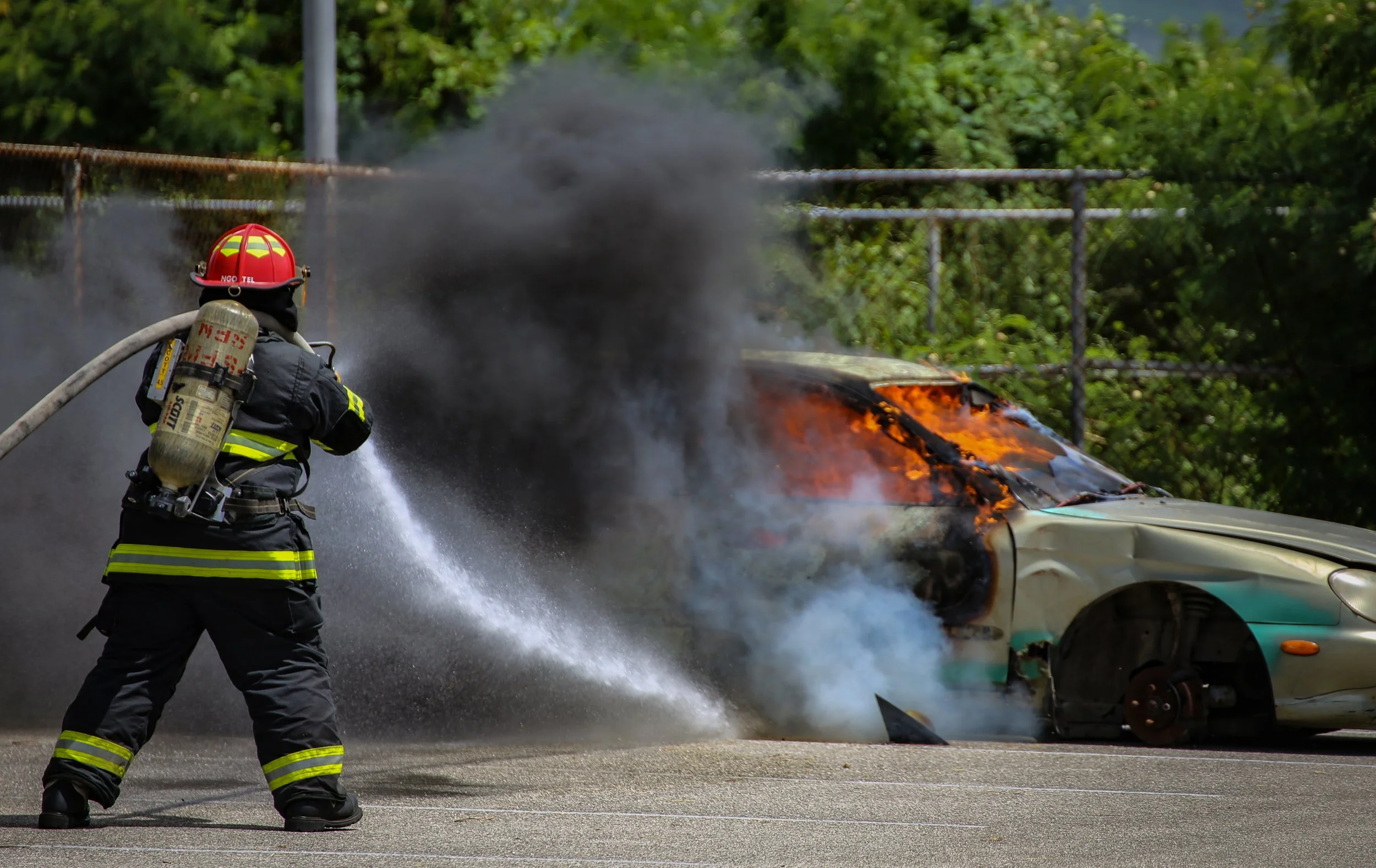 Enrique Ngotel, a firefighter with Saipan’s Department of Fire and Emergency Medical Services, extinguishes a car fire after an improvised explosive device detonated at Chacha Middle School in the Kagman neighborhood on the island of Saipan, Tuesday,