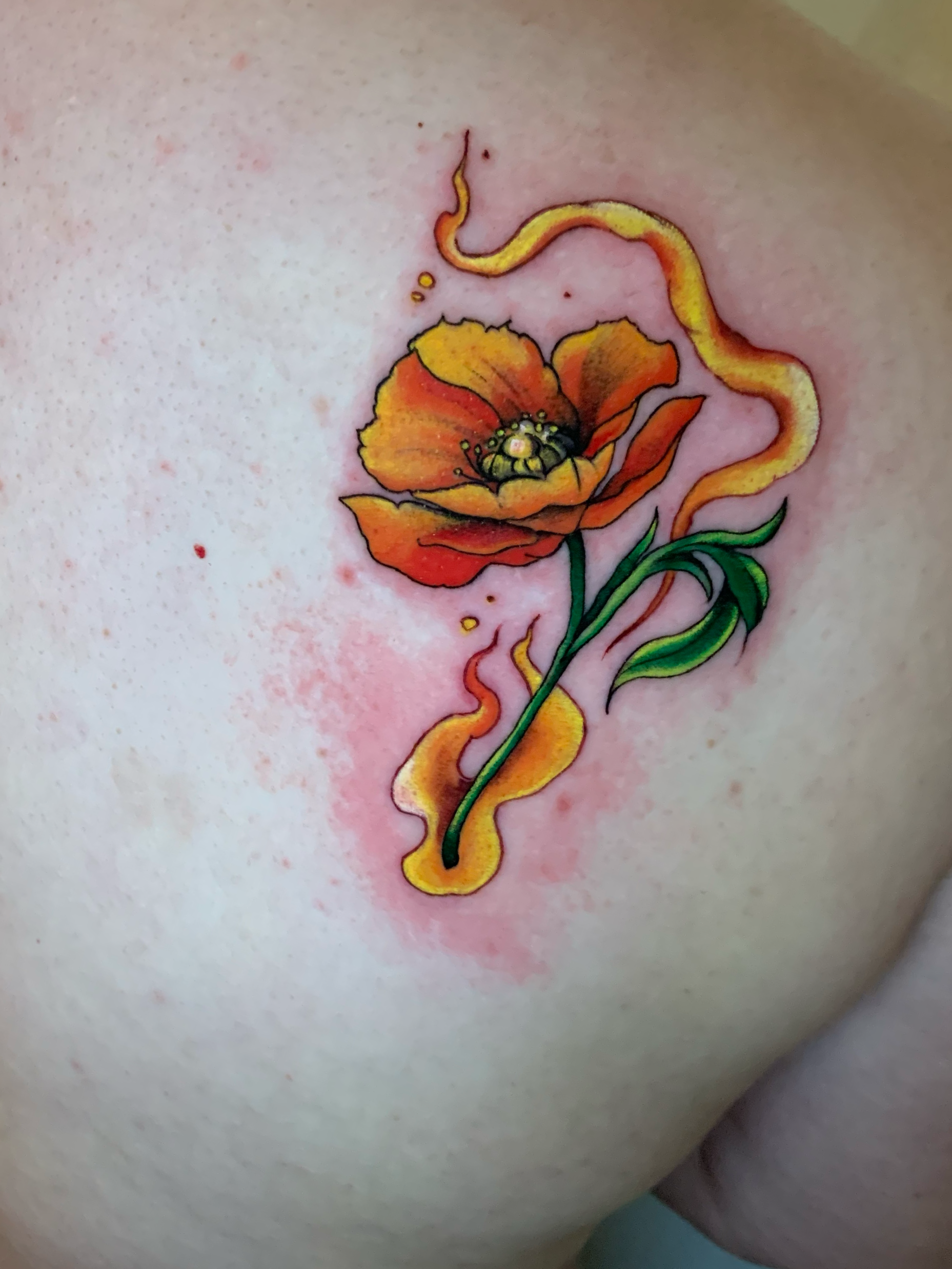 Color tattoo of an orange poppy and yellow ribbon on the shoulder
