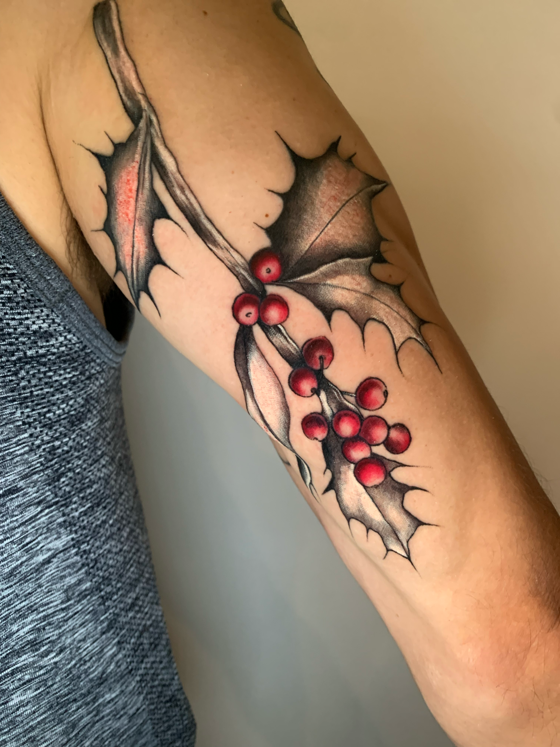Holly branch with red berries tattoo on the arm