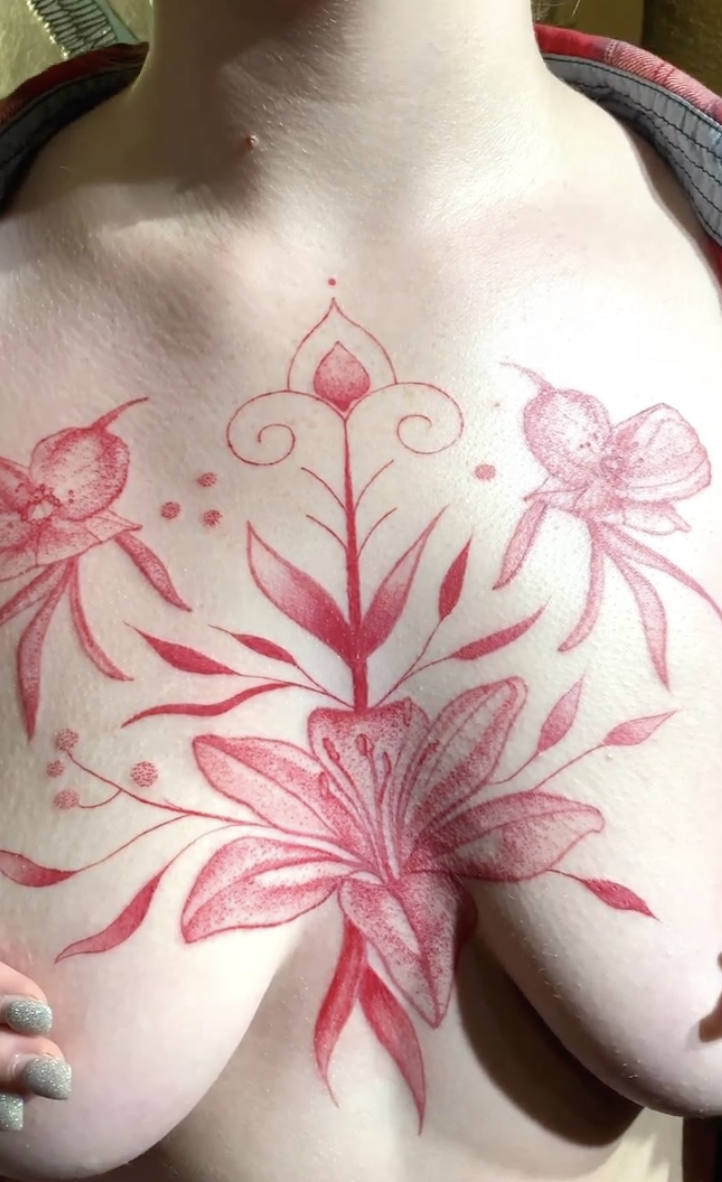 Red-ink ornamental floral tattoo across the chest
