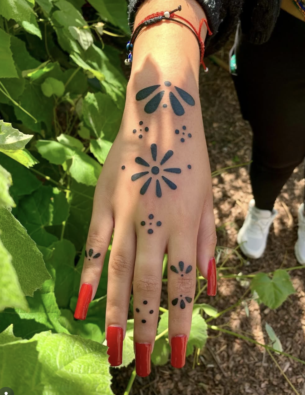 Hand tattoo of small dotted ornaments along the back of the hand and fingers