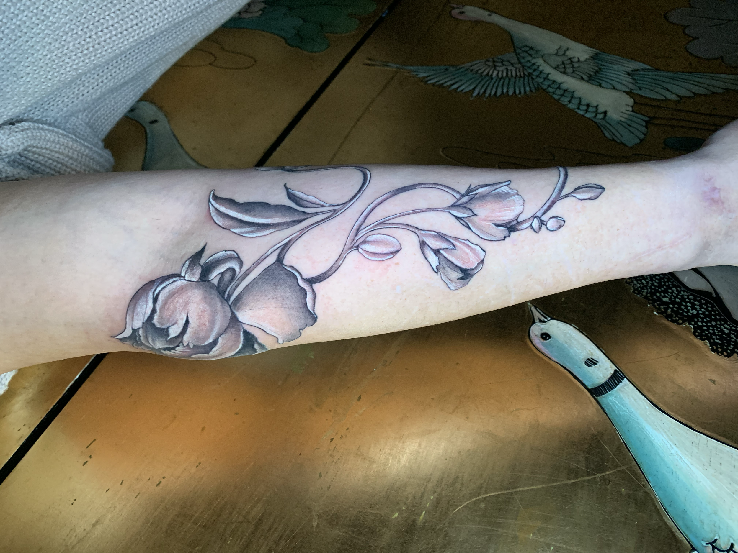 Close-up of a fine-line floral tattoo on the forearm