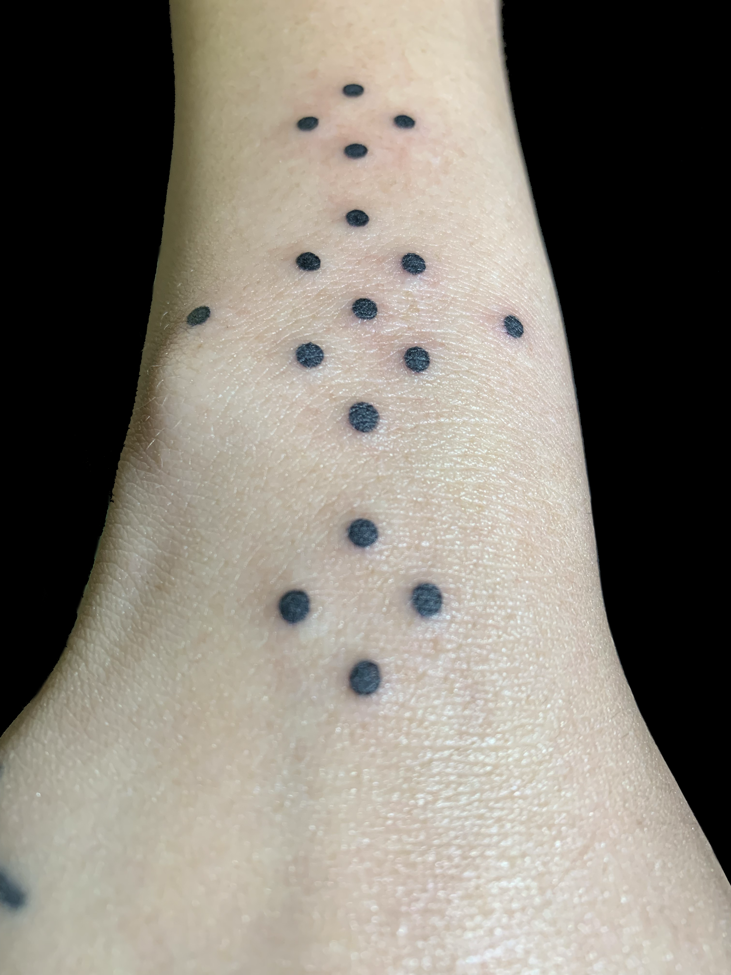 Dotted ornamental pattern tattoo on the inner forearm